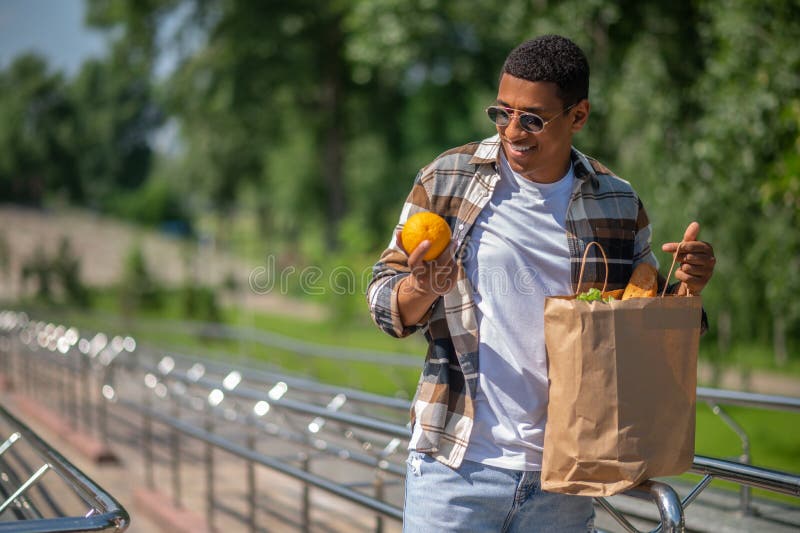 Jeune homme à la peau foncée avec un sac en papier de nourriture images stock