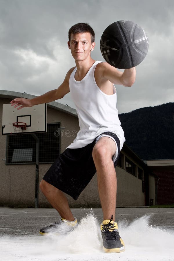 Young stylish teenage basketball player on the street with dark clouds over him. Young stylish teenage basketball player on the street with dark clouds over him.