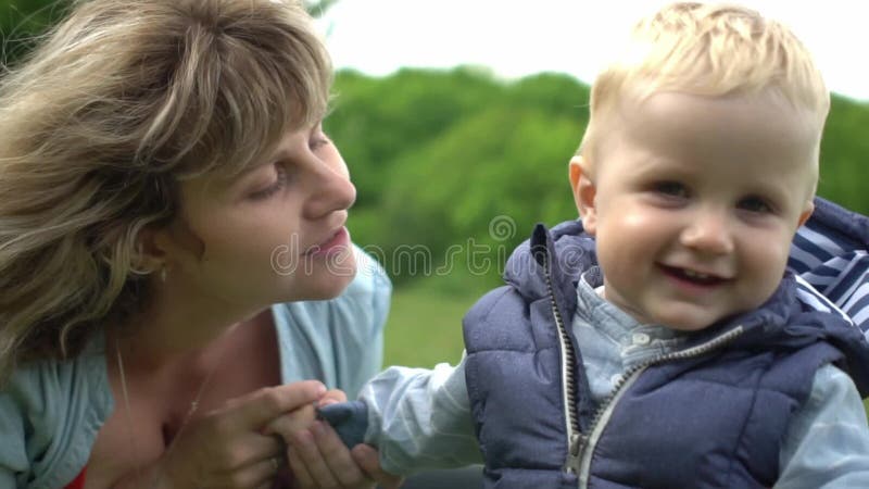 Jeune maman heureuse montrant l'amour et l'affection à son fils En parc