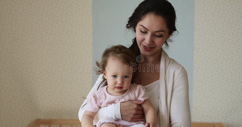Jeune maman hispanique joyeuse tenir une petite fille mignonne en armes banque de vidéos