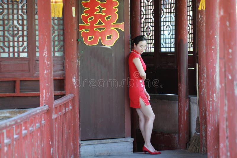 Jeune mariée chinoise heureuse dans le cheongsam rouge au jour du mariage traditionnel photo libre de droits Jeune mariée chinoise heureuse dans le cheongsam rouge au jour du mariage traditionnel photo libre de droits