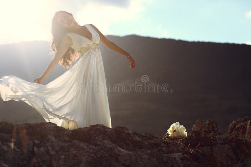 A beautiful young bride posing on top of a mountain at sunset. Made use of the almost magic light and soft focus. A beautiful young bride posing on top of a mountain at sunset. Made use of the almost magic light and soft focus.