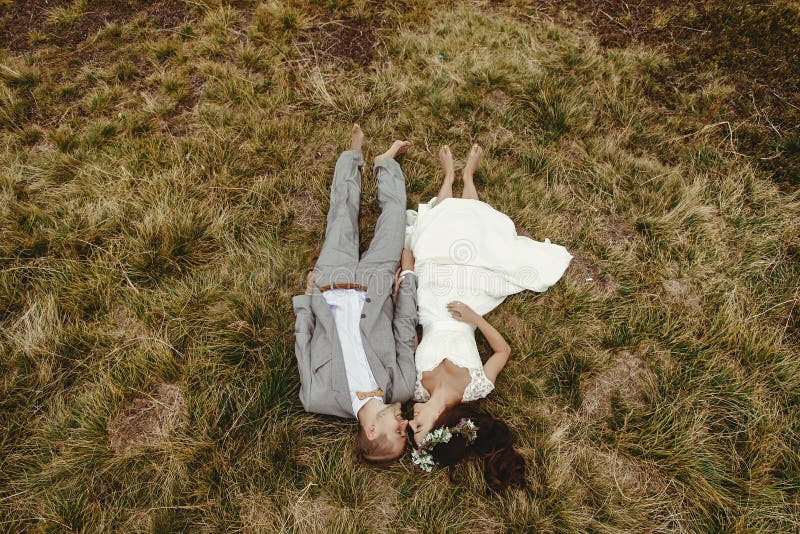 Jeune mariée magnifique et marié élégant se trouvant sur le dessus, cou de mariage de boho image libre de droits Jeune mariée magnifique et marié élégant se trouvant sur le dessus, cou de mariage de boho image libre de droits