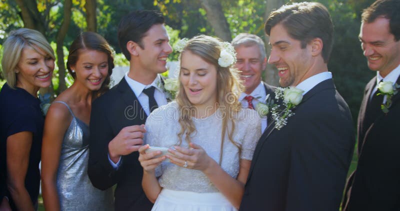 Jeune mariée, marié heureux et famille vérifiant les photographies 4K 4k