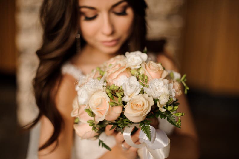 Jeune mariée mignonne tenant le bouquet de mariage du blanc et des roses de pêche photographie stock Jeune mariée mignonne tenant le bouquet de mariage du blanc et des roses de pêche photographie stock
