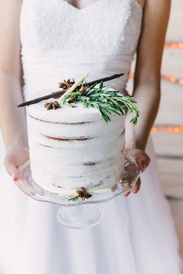 Jeune mariée tenant un gâteau de métier sur un support en verre photo stock Jeune mariée tenant un gâteau de métier sur un support en verre photo stock