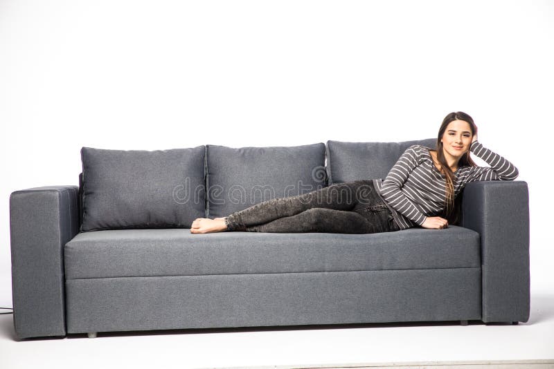 Jeune mensonge femelle sur un sofa d'isolement sur le fond blanc photographie stock Jeune mensonge femelle sur un sofa d'isolement sur le fond blanc photographie stock
