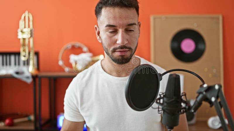 Jeune musicien arabe chantant dans un studio de musique