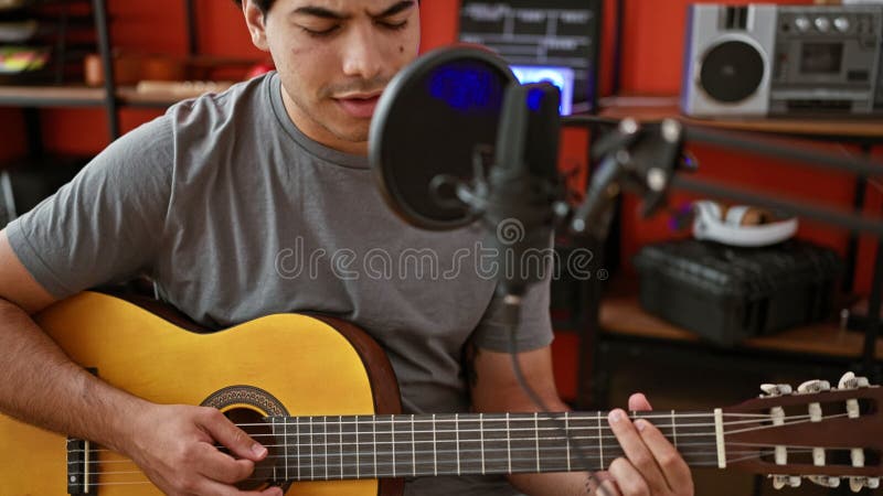 Jeune musicien latin chantant une chanson jouant de la guitare classique au studio de musique