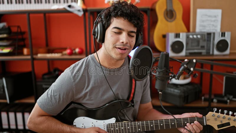 Jeune musicien latin chantant une chanson jouant de la guitare électrique au studio de musique