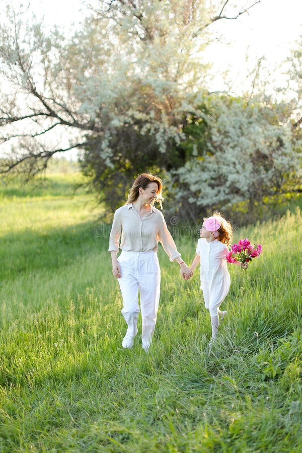 Jeune mère américaine marchant avec petite fille dans l'herbe. photographie stock
