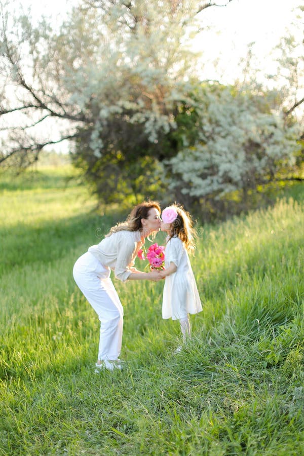 Jeune mère blonde embrasser petite fille dans l'herbe. photo libre de droits