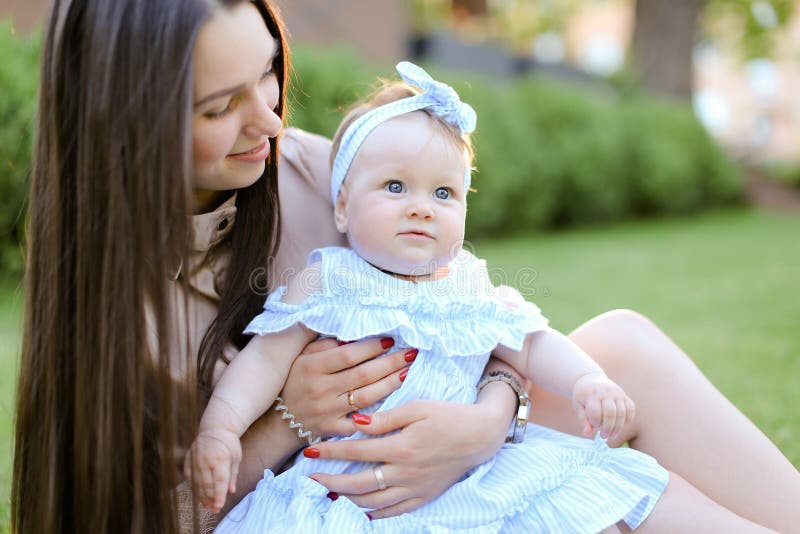 Jeune mère caucasienne s'asseyant sur l'herbe avec peu de fille photo stock Jeune mère caucasienne s'asseyant sur l'herbe avec peu de fille photo stock