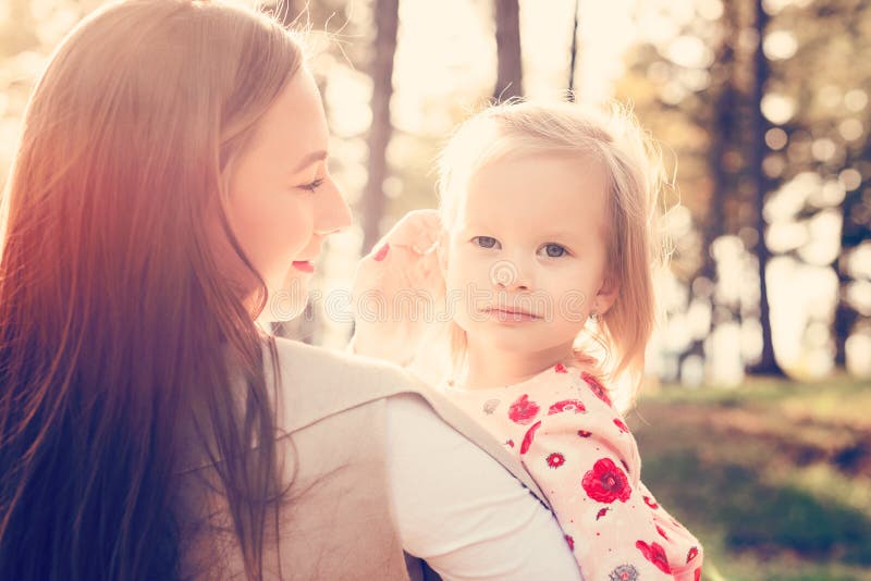 Jeune mère célibataire tenant la fille mignonne de fille d'enfant en bas âge dans des ses bras et frottant ses cheveux, concept d images stock Jeune mère célibataire tenant la fille mignonne de fille d'enfant en bas âge dans des ses bras et frottant ses cheveux, concept d images stock