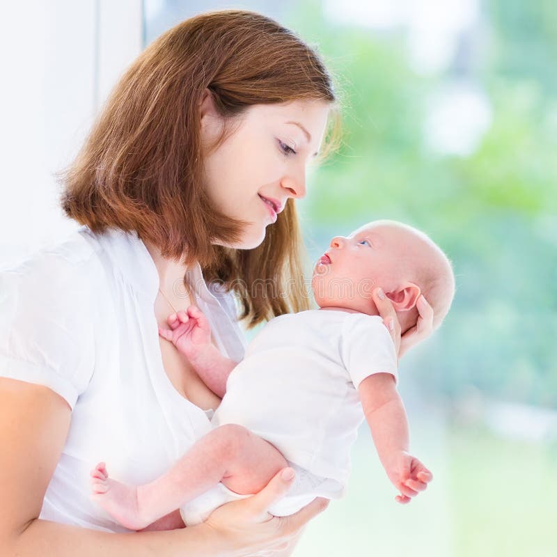Jeune mère et son bébé nouveau-né à la grande fenêtre photo libre de droits Jeune mère et son bébé nouveau-né à la grande fenêtre photo libre de droits