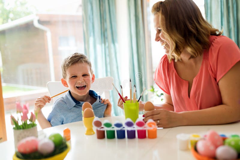 Jeune mère et son fils ayant l'amusement tandis que la peinture eggs pour Pâques images libres de droits Jeune mère et son fils ayant l'amusement tandis que la peinture eggs pour Pâques images libres de droits