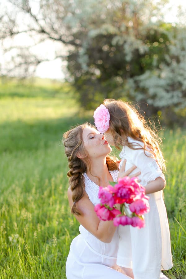 Jeune mère heureuse embrassant petite fille dans l'herbe. photo libre de droits