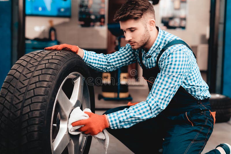 Jeune mécanicien Cleans Car Tire à la station service photos libres de droits Jeune mécanicien Cleans Car Tire à la station service photos libres de droits