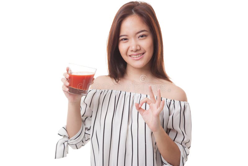 Jeune OK asiatique d'exposition de femme avec le jus de tomates
