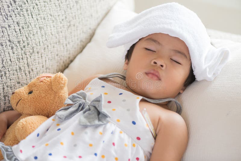Jeune petit sommeil et malade de fille sur le sofa avec un gel plus frais photos libres de droits Jeune petit sommeil et malade de fille sur le sofa avec un gel plus frais photos libres de droits