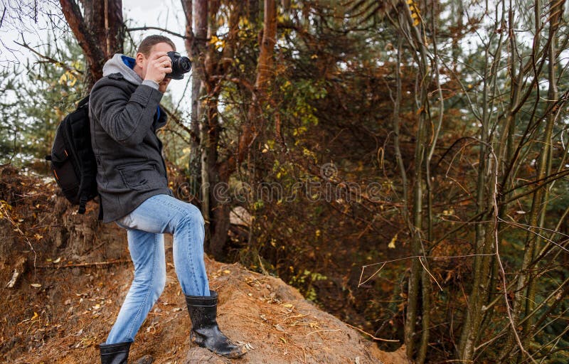 Jeune photographe photographiant dans la forêt d'automne image stock Jeune photographe photographiant dans la forêt d'automne image stock