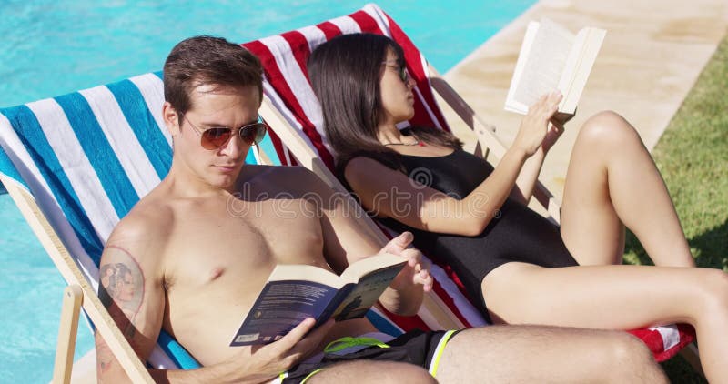 Jeune poolside attrayant décontracté de lecture de couples banque de vidéos