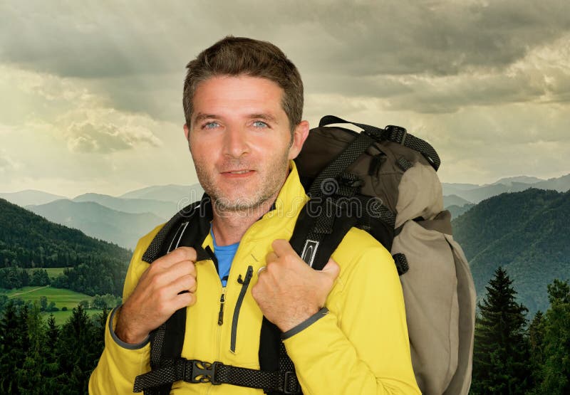 Jeune pose de transport de sac à dos d'homme heureux et attirant de randonneur gaie pendant la hausse de montagne souriant appréc image stock Jeune pose de transport de sac à dos d'homme heureux et attirant de randonneur gaie pendant la hausse de montagne souriant appréc image stock