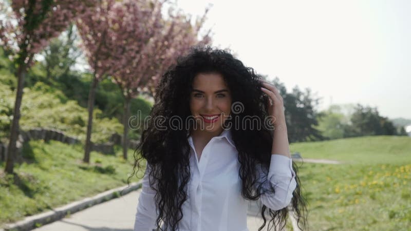 Jeune promenade magnifique de femme dans le mouvement lent en parc de floraison banque de vidéos