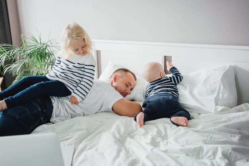 Jeune père heureux allongé sur le lit pendant que sa fille joue avec lui photos libres de droits Jeune père heureux allongé sur le lit pendant que sa fille joue avec lui photos libres de droits