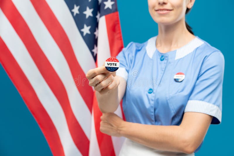 Jeune roommaid en uniforme montrant les insignes de vote contre les starsandstripes photos stock
