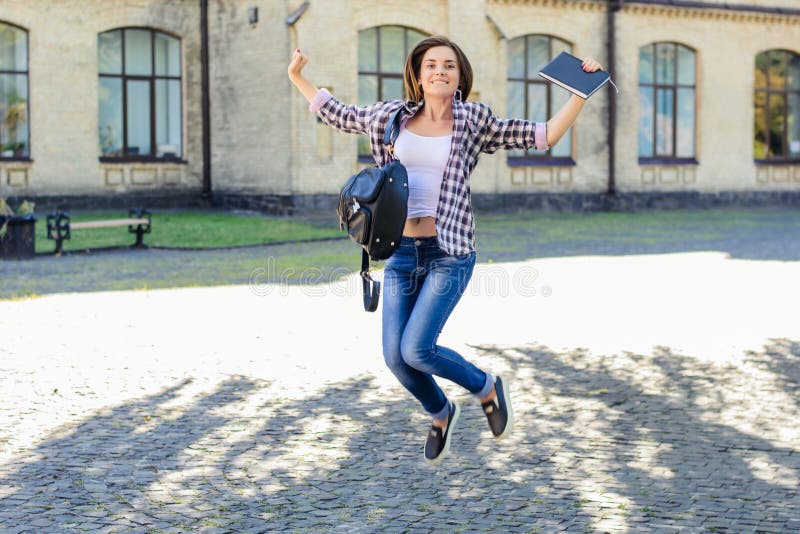 Jeune sauter enthousiaste de sourire heureux d'étudiante, célébrant image libre de droits Jeune sauter enthousiaste de sourire heureux d'étudiante, célébrant image libre de droits