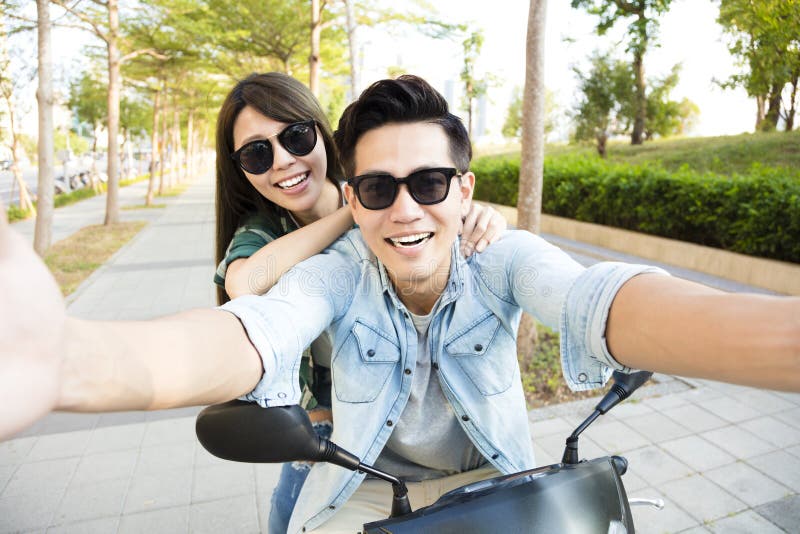 Jeune scooter heureux d'équitation de couples et fabrication de la photo de selfie images libres de droits