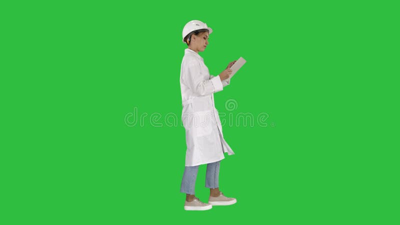 Jeune technicien inspectant et prenant les notes nécessaires sur le comprimé numérique sur un écran vert, clé de chroma banque de vidéos