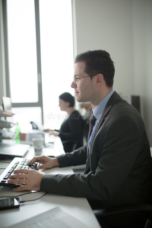 Jeune travail heureux d'homme d'affaires dans le bureau moderne Homme d'affaires bel In Office Vrais bussinesmen d'économiste, pa image stock Jeune travail heureux d'homme d'affaires dans le bureau moderne Homme d'affaires bel In Office Vrais bussinesmen d'économiste, pa image stock