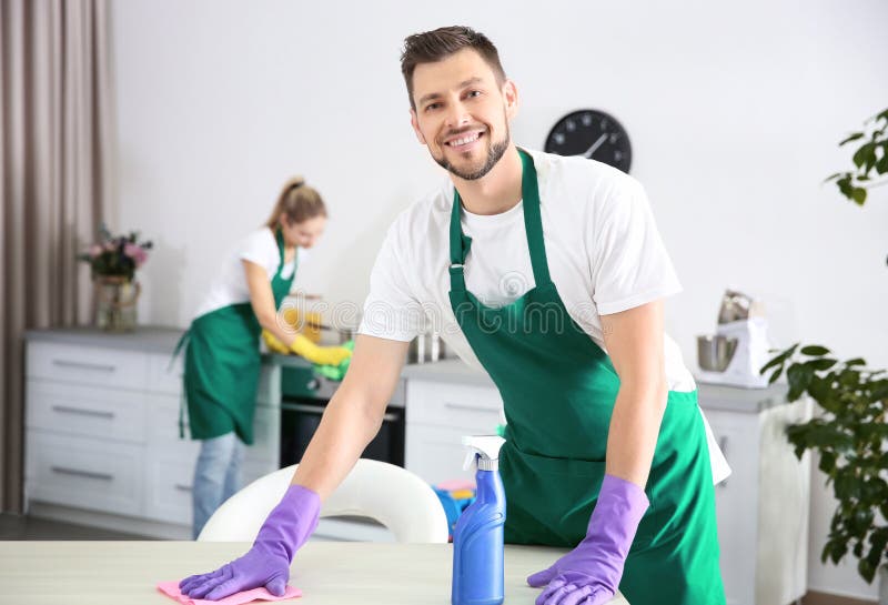 Jeune travailleur de sexe masculin de service de nettoyage travaillant dans la cuisine photographie stock libre de droits Jeune travailleur de sexe masculin de service de nettoyage travaillant dans la cuisine photographie stock libre de droits