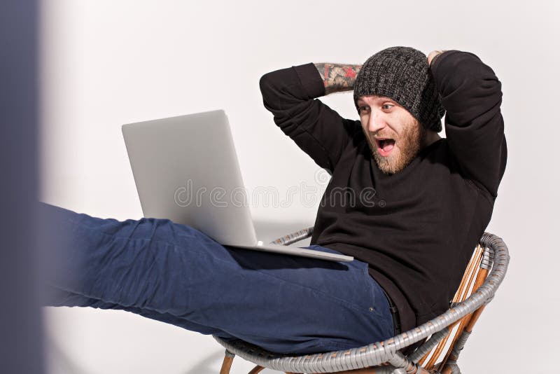 Jeune type avec une barbe avec un ordinateur portable photos stock Jeune type avec une barbe avec un ordinateur portable photos stock