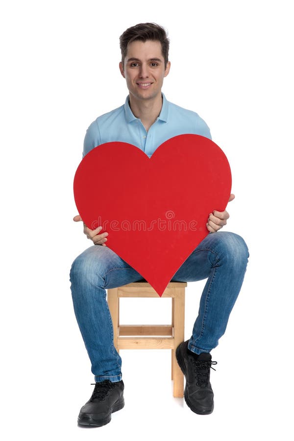 Jeune type gai tenant une forme et un sourire de coeur photos stock Jeune type gai tenant une forme et un sourire de coeur photos stock