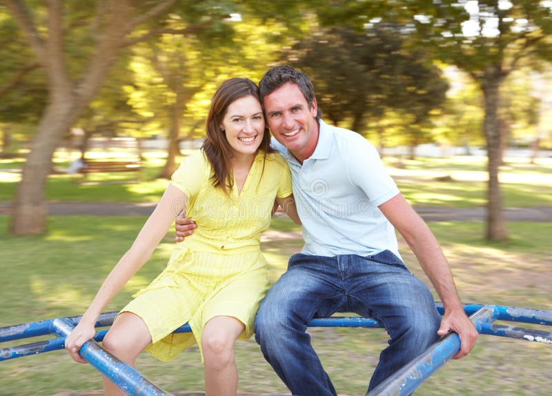Jeune équitation de couples sur le rond point en stationnement image stock Jeune équitation de couples sur le rond point en stationnement image stock