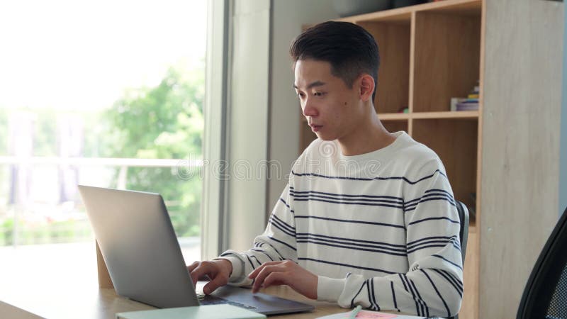 Jeune étudiant asiatique assis à l'aide d'ordinateur portable pc sur le campus universitaire moderne.