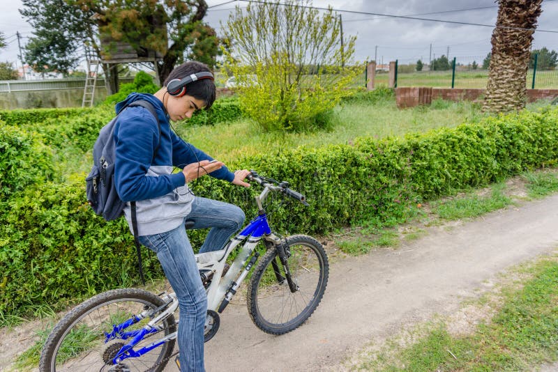 Jeune étudiant avec le sac à dos et la bicyclette, écoutant la musique photos libres de droits Jeune étudiant avec le sac à dos et la bicyclette, écoutant la musique photos libres de droits