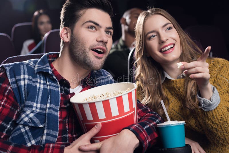 young smiling couple with popcorn watching movie in cinema. young smiling couple with popcorn watching movie in cinema