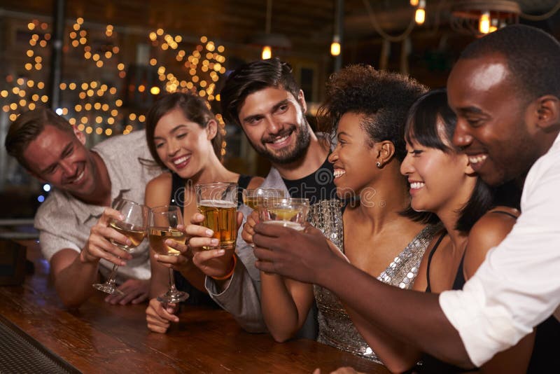 Jeunes amis adultes faisant un pain grillé par la barre à une partie photos libres de droits Jeunes amis adultes faisant un pain grillé par la barre à une partie photos libres de droits
