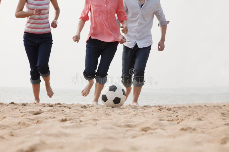 Jeunes amis jouant le football sur la plage photos libres de droits Jeunes amis jouant le football sur la plage photos libres de droits