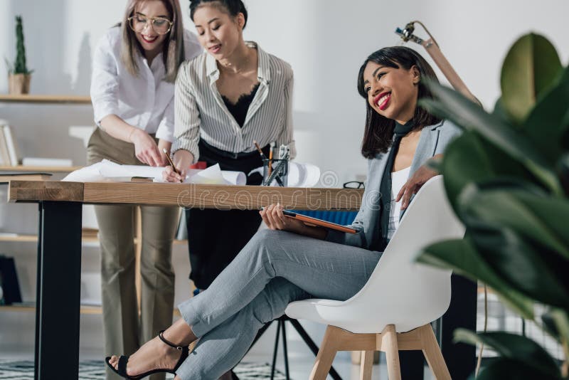 Jeunes architectes dans le tenue de soirée fonctionnant avec le modèle et le comprimé numérique dans le bureau photos stock