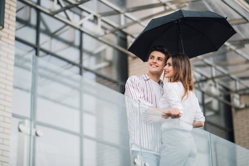 Jeunes beaux couples regardant l'un l'autre avec amour sous le parapluie dans le jour pluvieux dans la rue Relations d'amour et d photo stock Jeunes beaux couples regardant l'un l'autre avec amour sous le parapluie dans le jour pluvieux dans la rue Relations d'amour et d photo stock