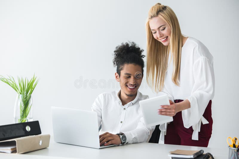 jeunes collègues multi-ethniques heureux d'affaires travaillant avec les dispositifs numériques photographie stock jeunes collègues multi-ethniques heureux d'affaires travaillant avec les dispositifs numériques photographie stock
