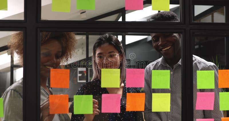 Jeunes collègues métisse heureux en travaillant ensemble à proximité du conseil kanban. banque de vidéos