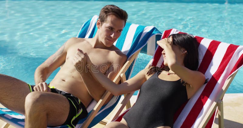 Jeunes couples affectueux prenant un bain de soleil dans des chaises de plate-forme banque de vidéos