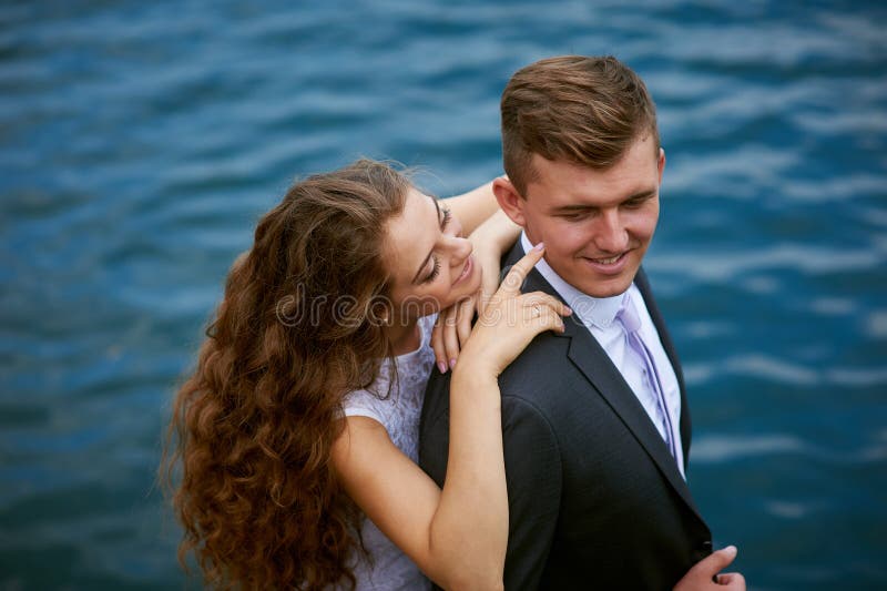 Jeunes couples affectueux sur une promenade près du lac leur jour du mariage image libre de droits Jeunes couples affectueux sur une promenade près du lac leur jour du mariage image libre de droits