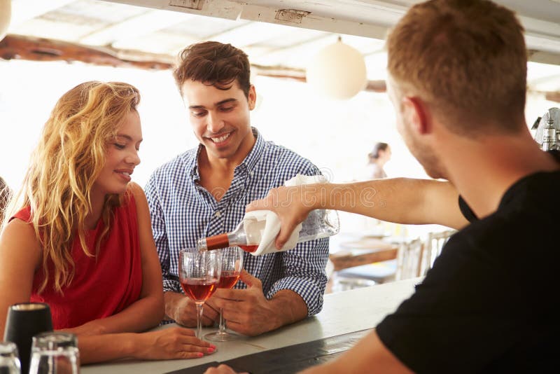 Jeunes couples appréciant la boisson à la barre extérieure image libre de droits Jeunes couples appréciant la boisson à la barre extérieure image libre de droits